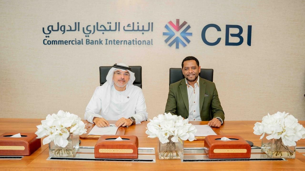 Michel Tzsfaldet signing a partnership agreement beneath the Commercial Bank International (CBI) logo in Dubai.